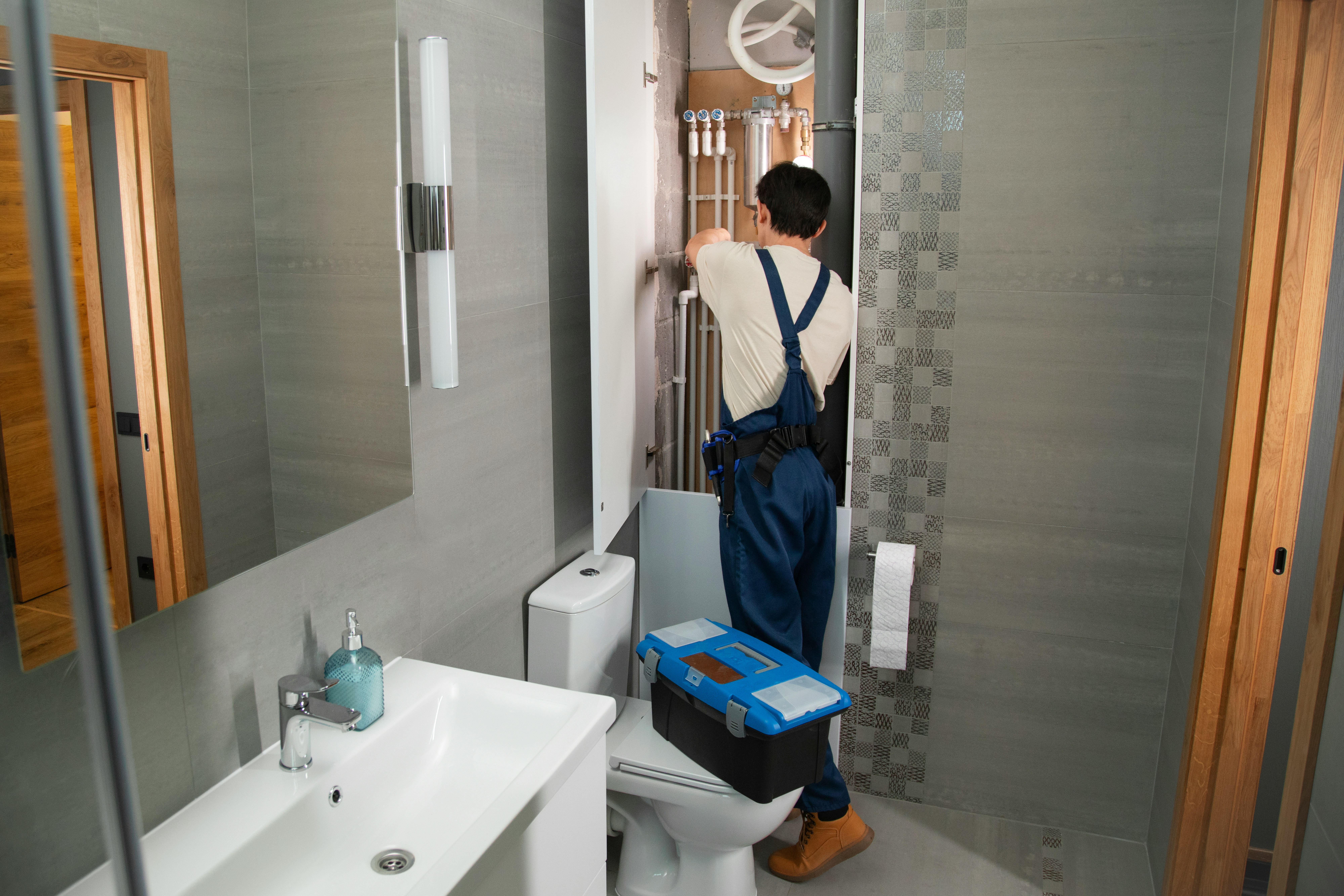 Plumber servicing pipes in a residential bathroom